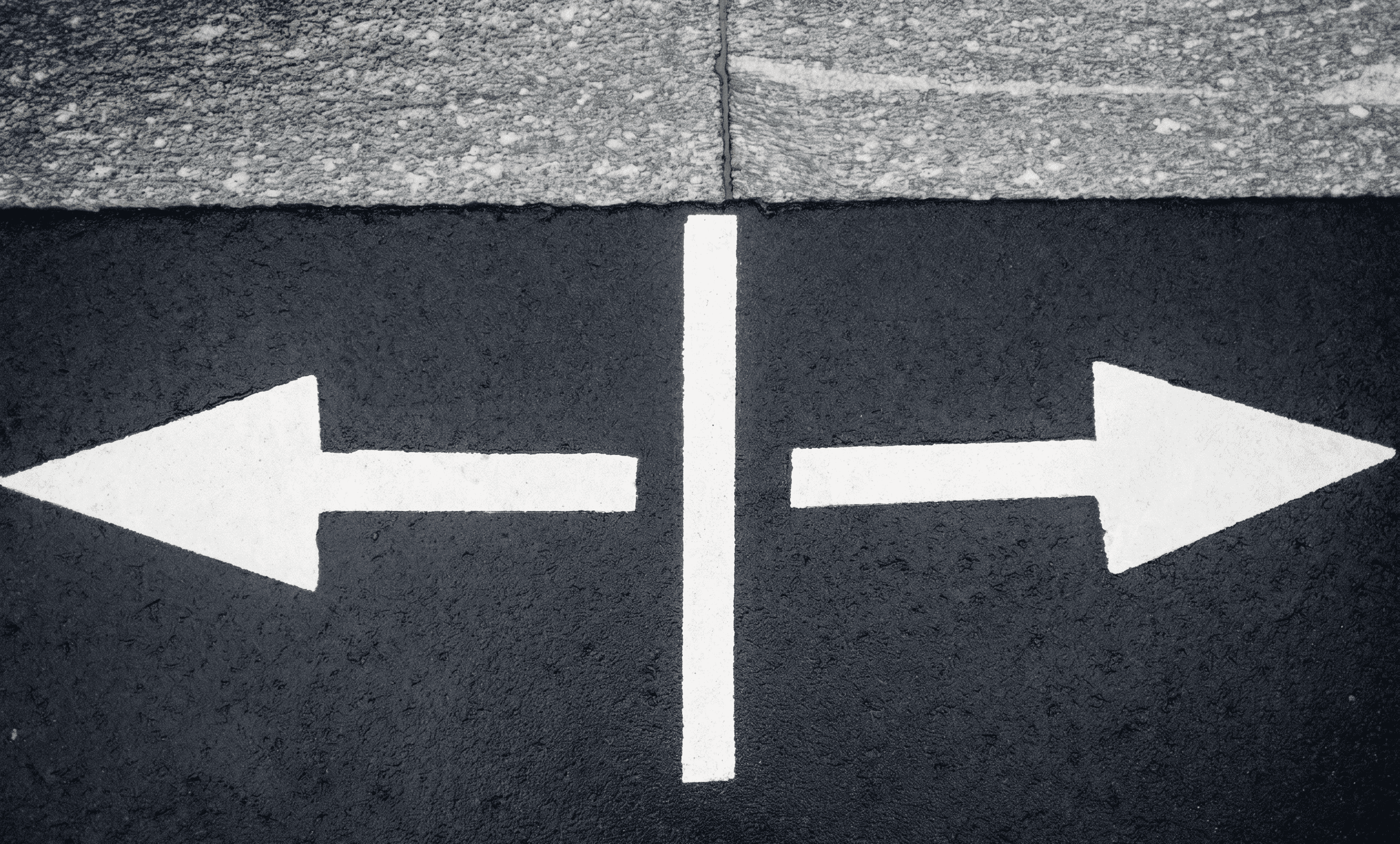 Flechas señalizando dos direcciones opuestas sobre asfalto